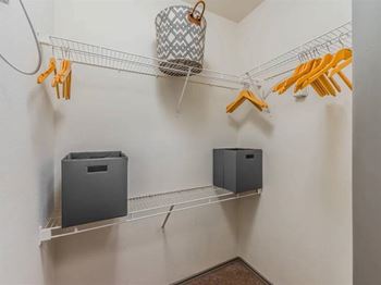 A laundry room with a white wall and a shelf with a basket and two boxes on it.